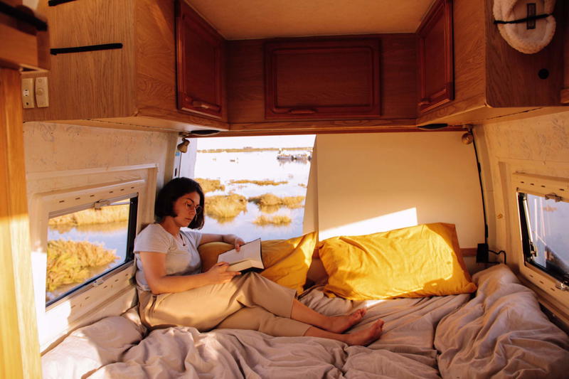 A woman sitting on a bed in a camper van.