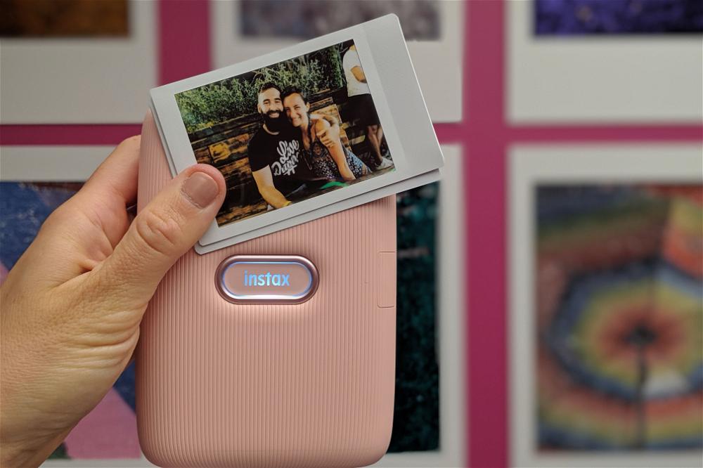 A person is holding up a pink polaroid camera.