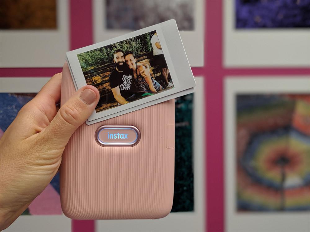 A person is holding up a pink polaroid camera.