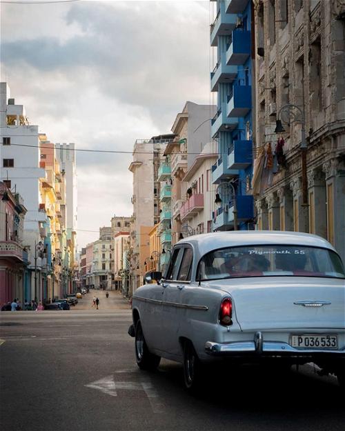 A classic car driving down a street in havana, cuba.