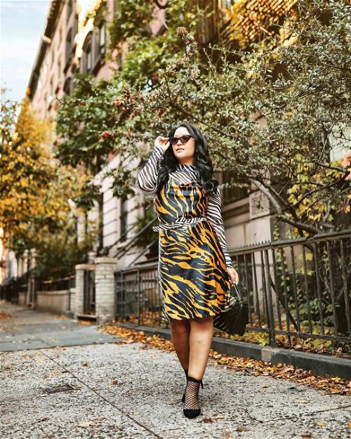 A woman in a tiger print dress walking down the street.