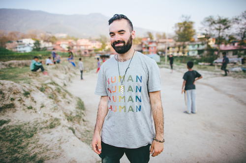 A man in a t - shirt standing in a dirt field.