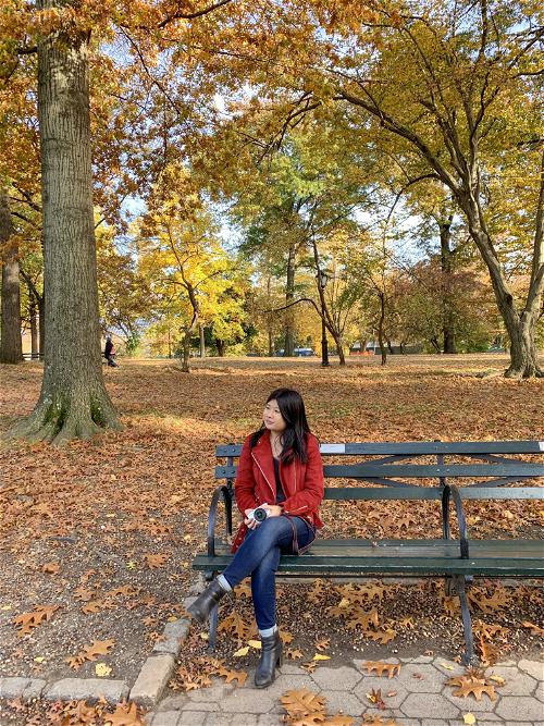 A woman sitting on a park bench in the fall.