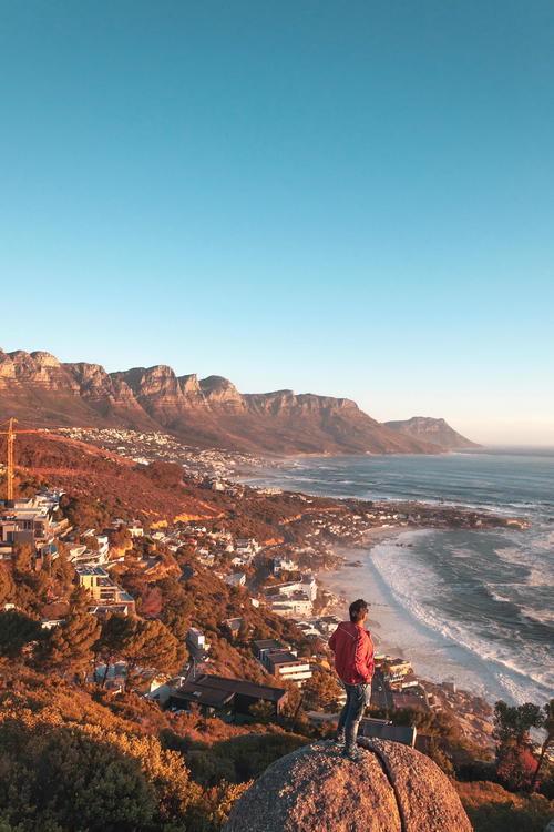 A man standing on top of a rock overlooking the ocean.