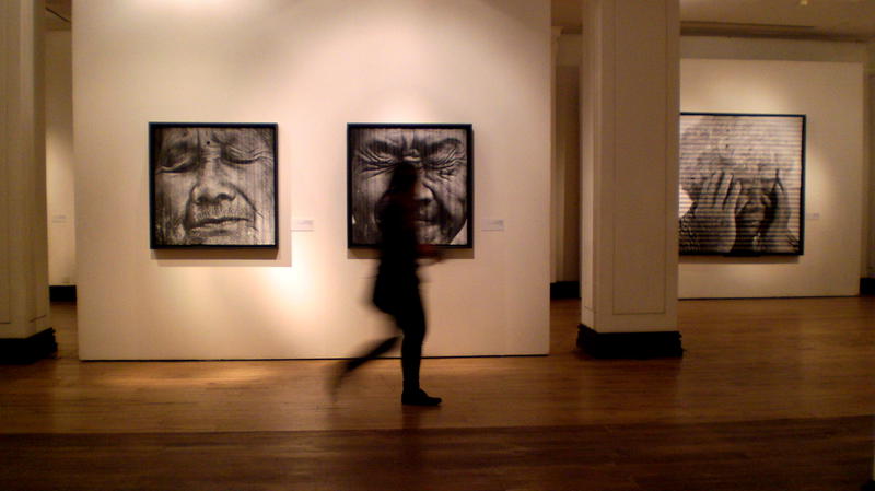 a person walking in an art gallery with paintings on the wall