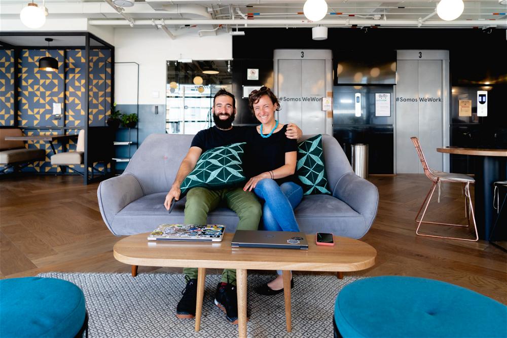 A man and woman sitting on a couch in an office.