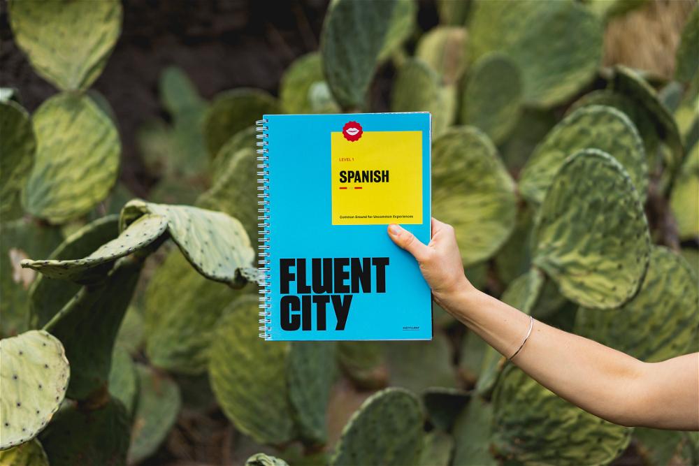 A person holding up a notebook with the word fluent city on it.