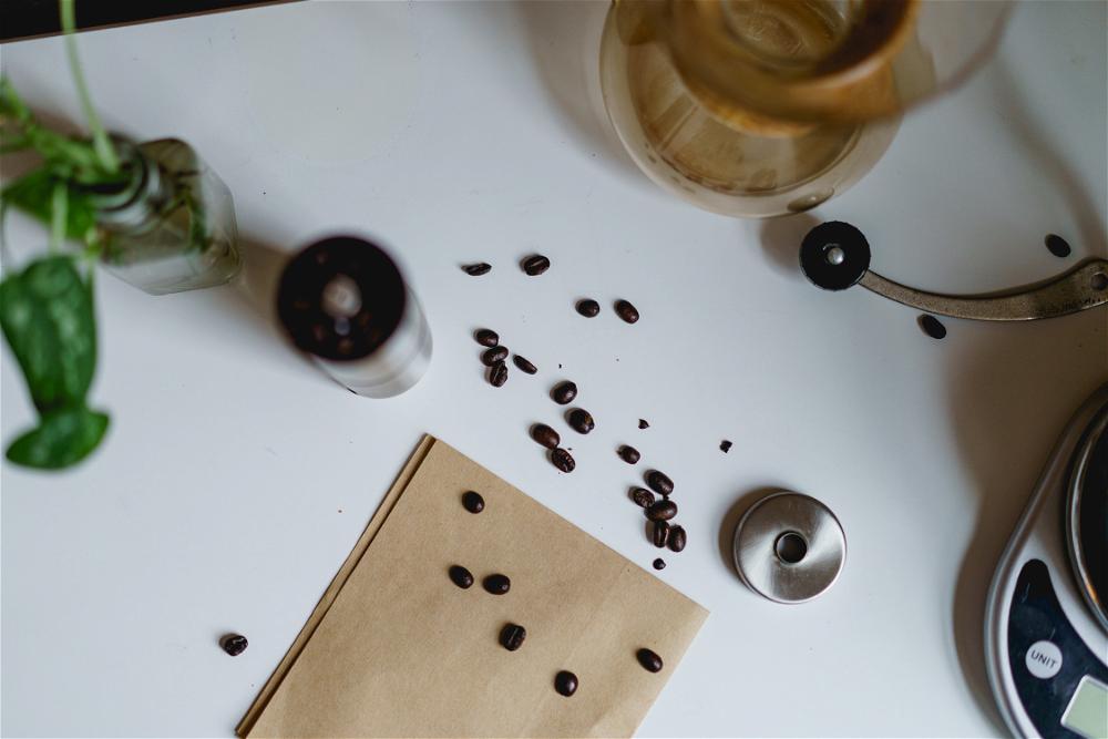 Coffee beans on a table next to a coffee maker.