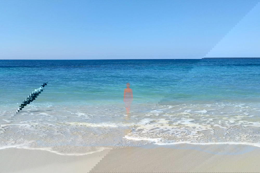 A woman standing on a beach looking at the ocean.