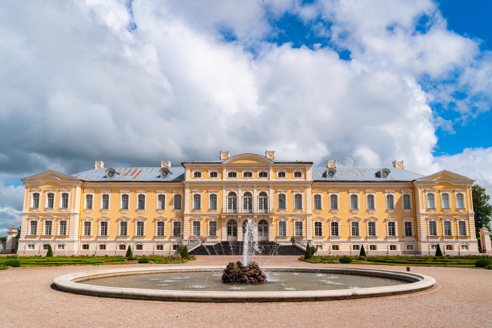 A large yellow building with a fountain in front of it.