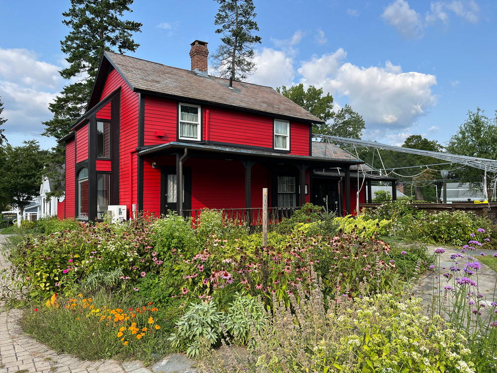 A red house with flowers in front of it.