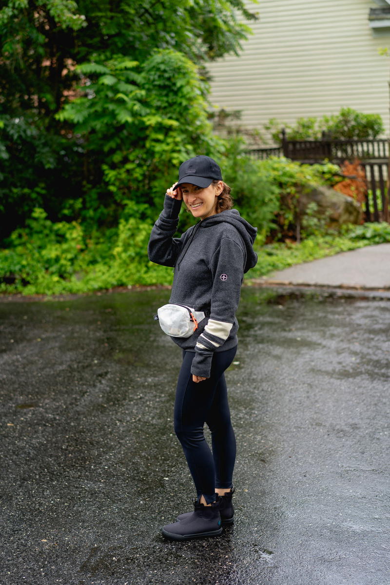 a woman walking in the rain wearing a fanny pack