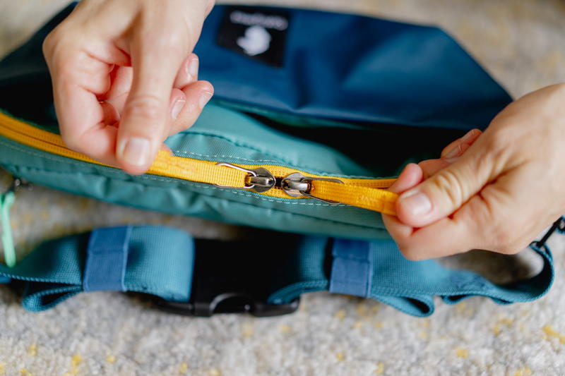 a person holding a zipper on a bag
