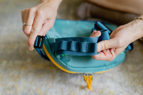 a person holding a blue bag with a yellow handle