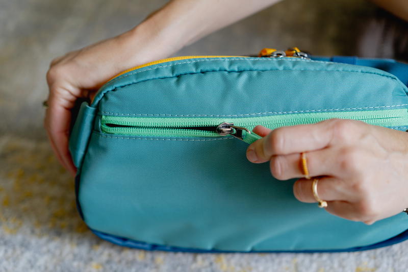 a person holding a small blue bag with a yellow zipper