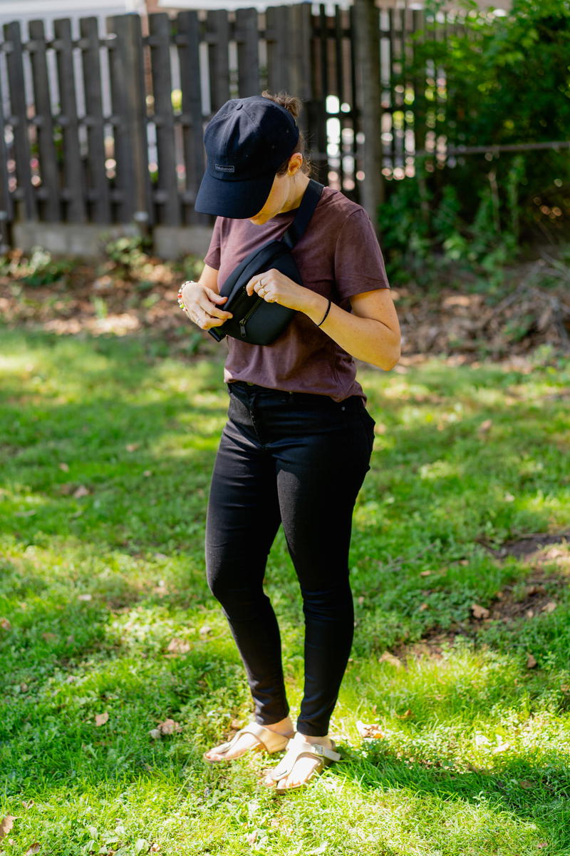 a woman in the grass wearing a fanny pack
