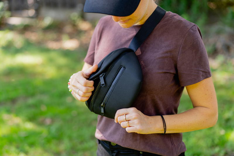 a woman in a brown shirt holding a black bag