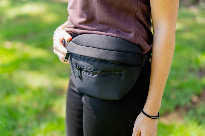 a woman in a brown shirt holding a black fanny bag