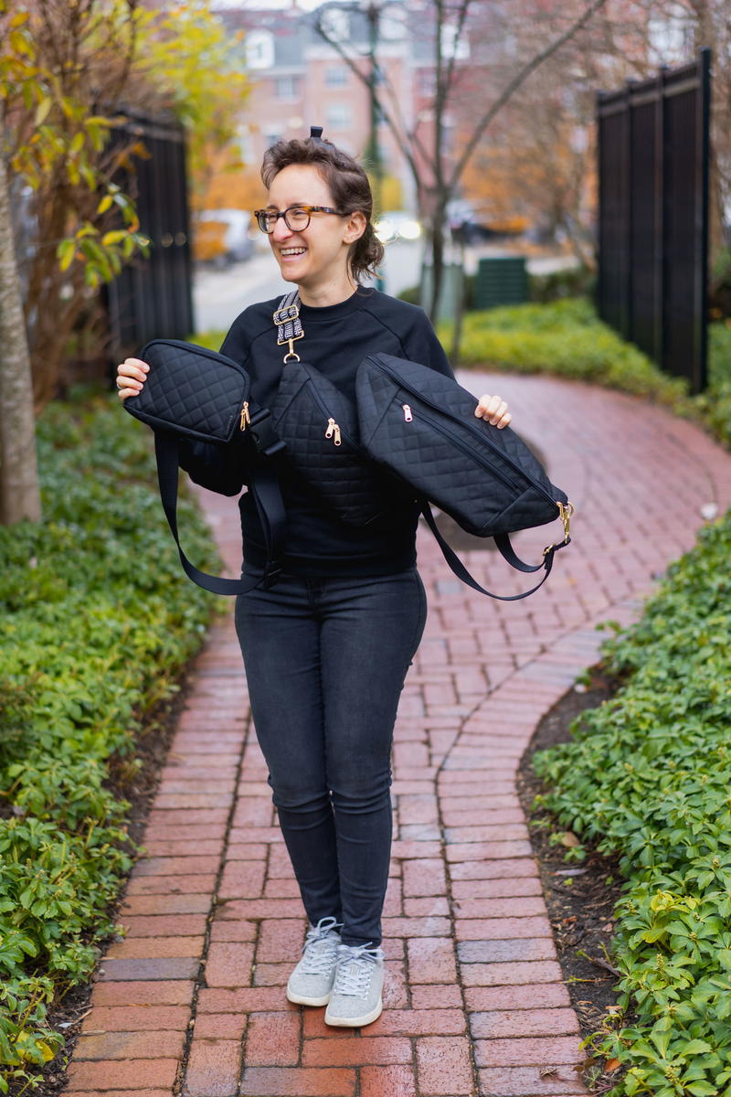 a woman walking down a brick path wearing a black jacket and white sneakers