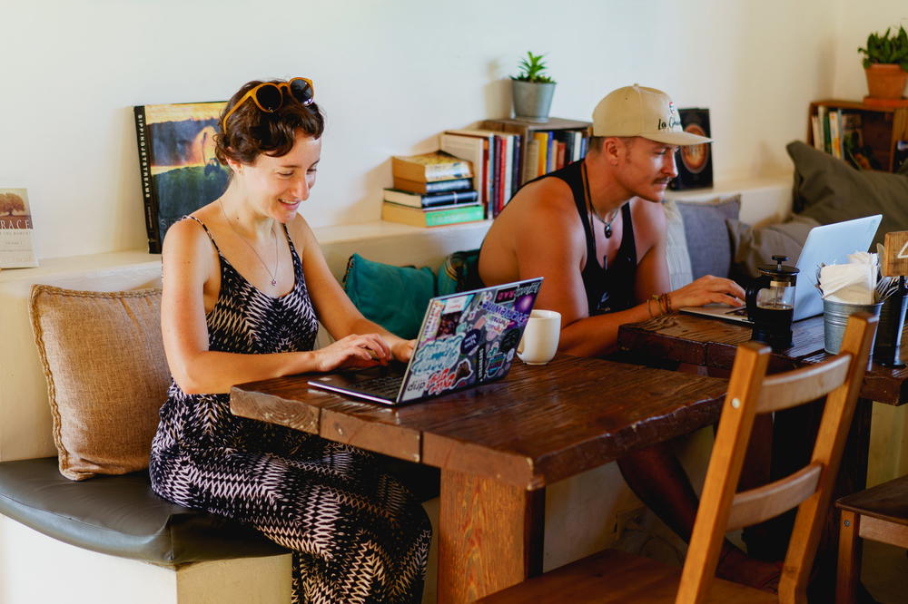 Woman working remotely with laptop at a trendy beach cafe