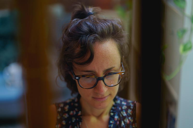 Woman focusing on work while working from home in a home office seen through the panes of a window