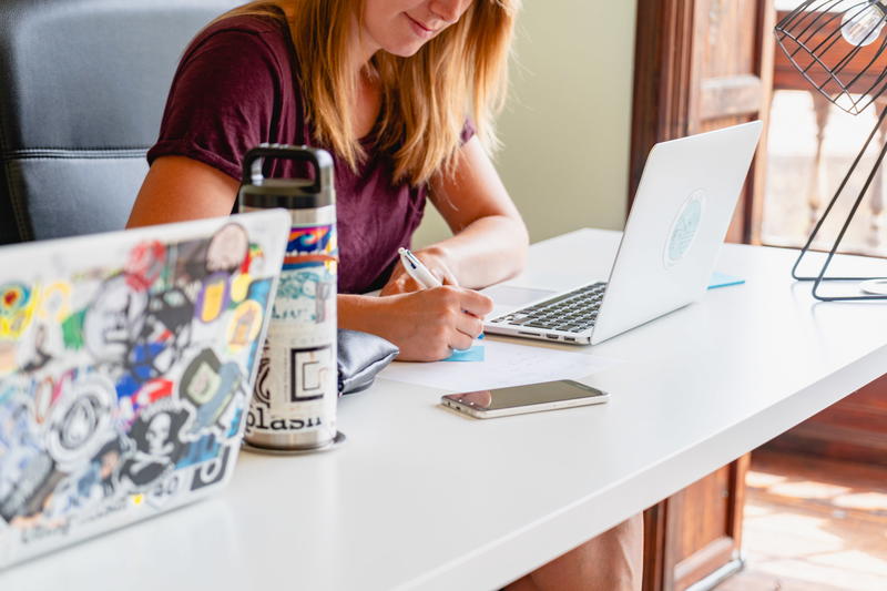 Blond girl working remotely in a coworking space from a shared communal table in natural light