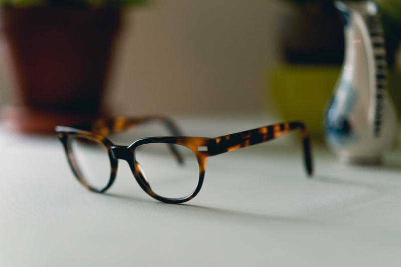 A pair of glasses on a table next to a plant.