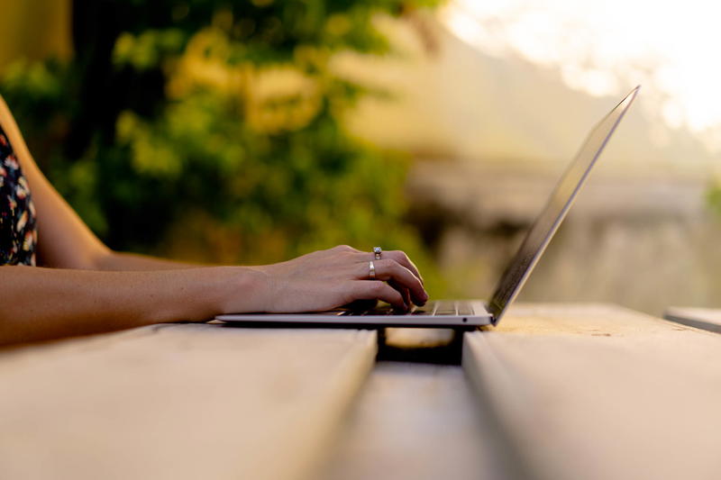 A woman is using a laptop on a wooden table.