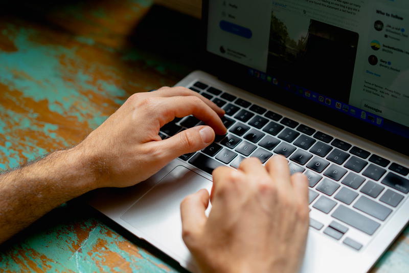 A person typing on a laptop keyboard.