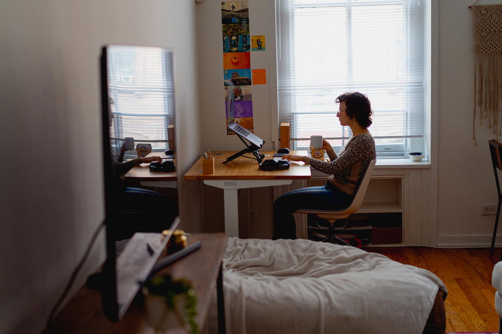 A woman working at a desk in a small room.