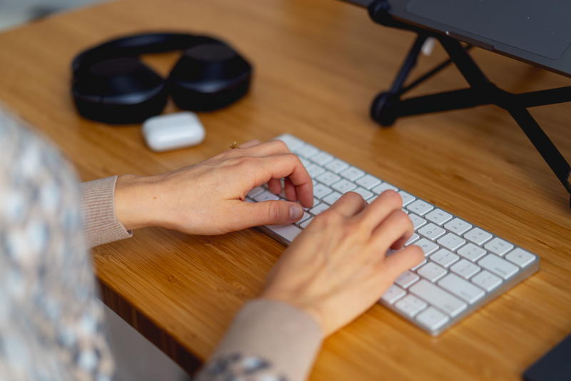 A woman's hands typing on a keyboard.