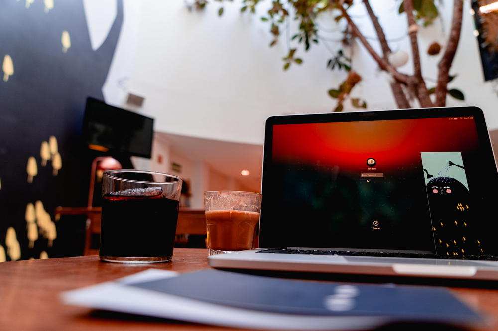 A laptop computer on a table with a cup of coffee.