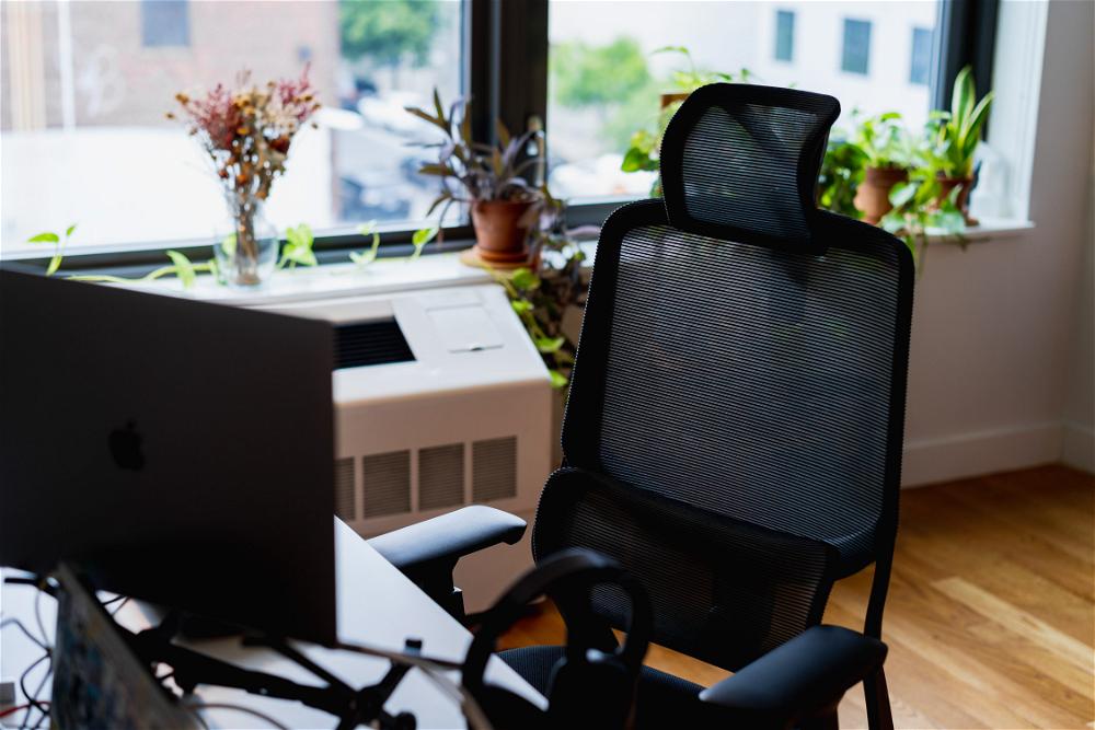 A black office chair in front of a window.