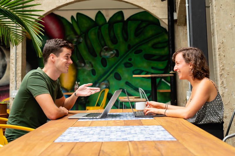 Digital nomad boy and girl sitting at a table having a conversation about remote work