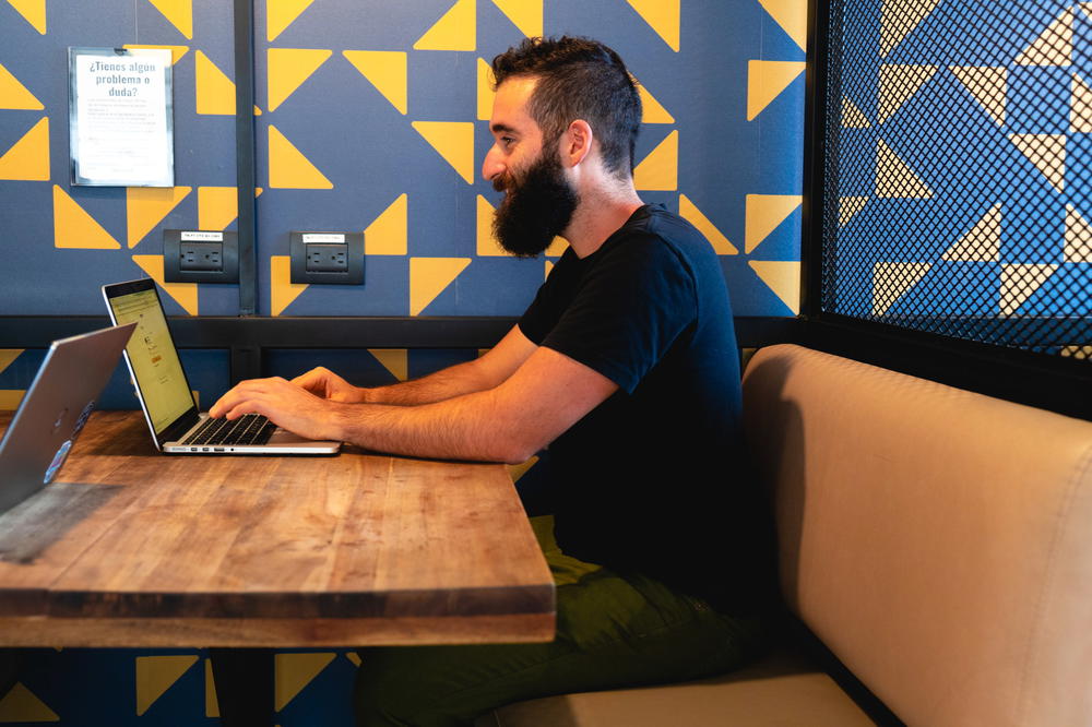 A man sitting at a table with a laptop.