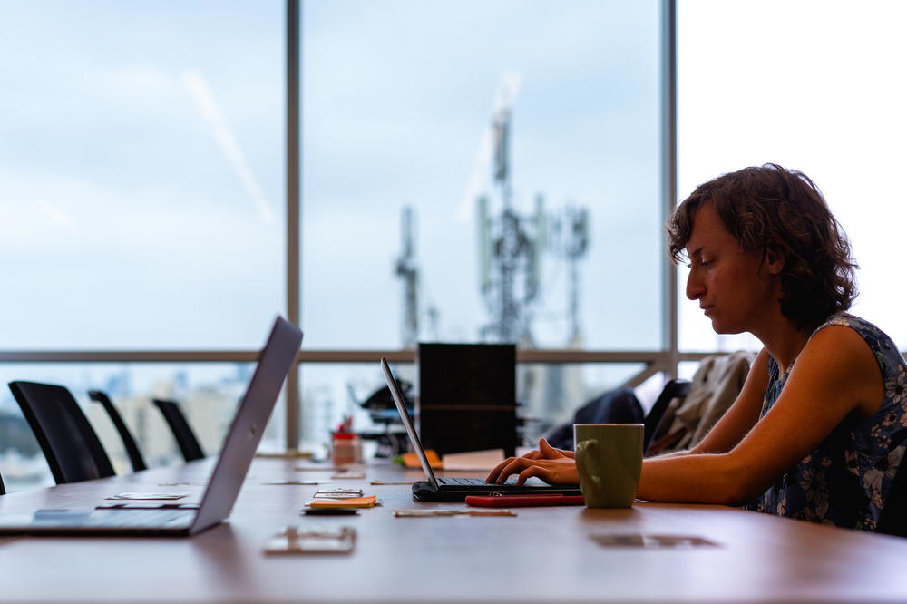 A woman working on a laptop in a conference room.