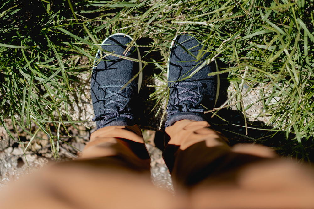 Close up of the Allbirds runner up mizzles in dark gray standing on a curb with grass