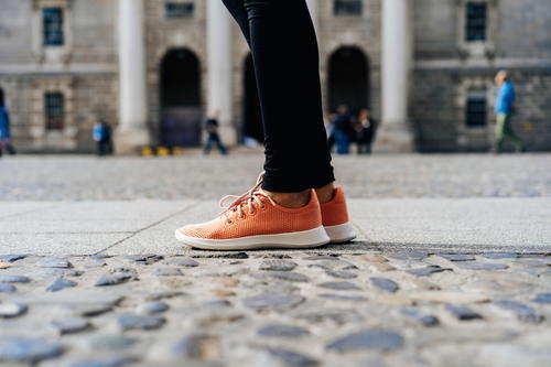 Orange Allbirds tree runners on a cobblestone street