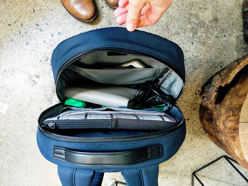 Blue Away Travel backpack on a wooden chair open with contents showing