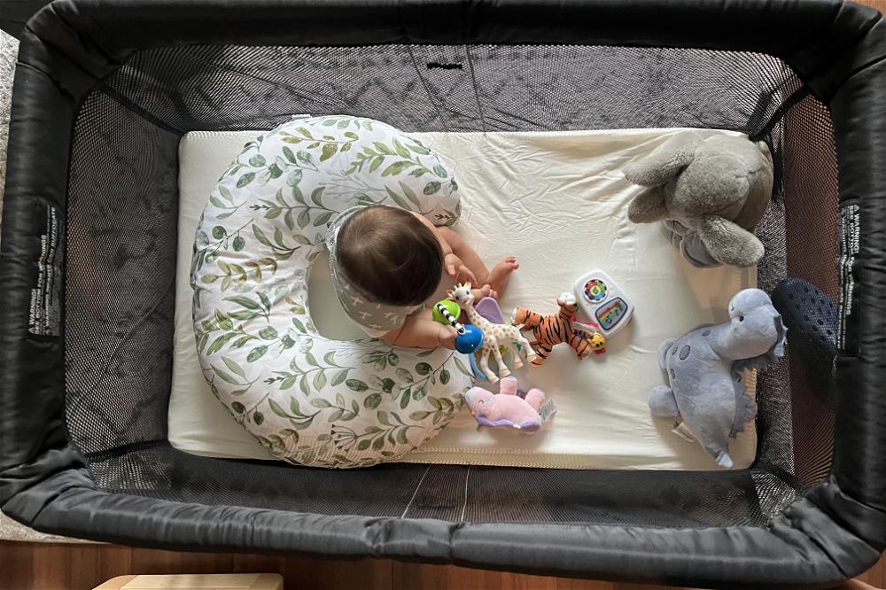 An infant in the Baby Bjorn travel crib playing with toys