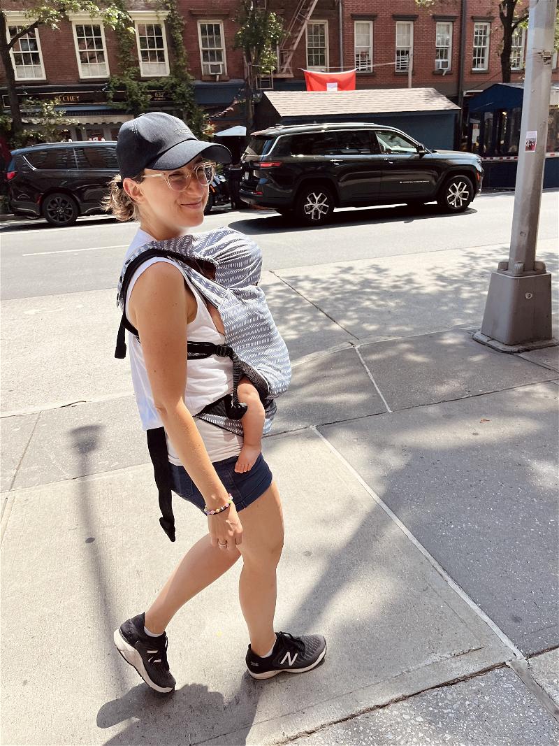 Woman walking in NYC wearing the baby Tula baby carrier