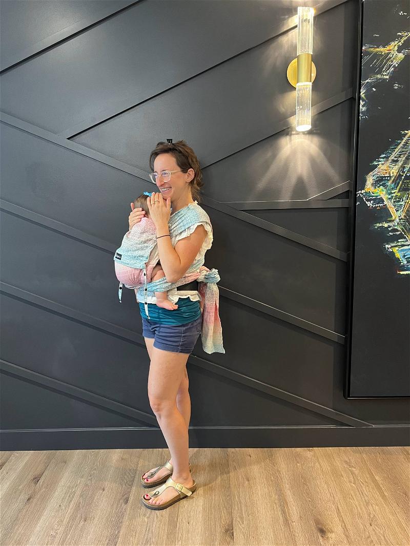Woman holding a baby and wearing a Didymos Didyklick baby carrier