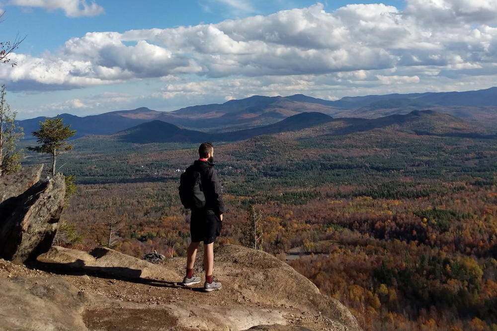 A man standing on top of a mountain overlooking a valley.