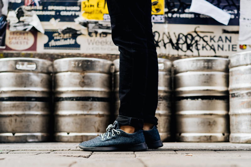 Man wearing the Allbirds wool runners with kegs in the background.