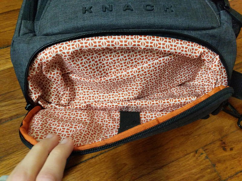 Opening the bottom zipper pocket used for storing laptop cables on the gray Small Expandable Knack Pack