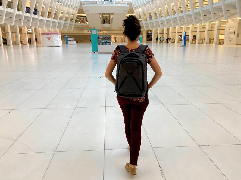 Woman wearing the gray Small Expandable Knack Pack while walking through the empty Oculus shopping mall at the world trade center transit hub