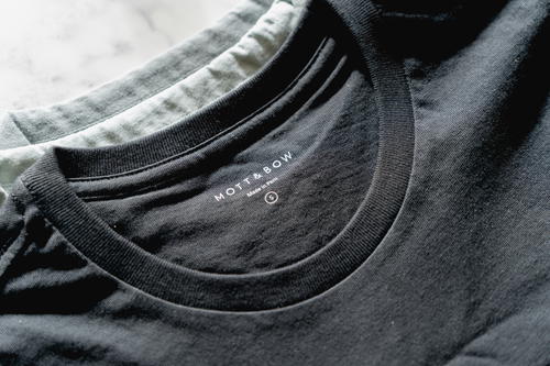 Two Mott & Bow t-shirts. A black shirt on top of a light green shirt