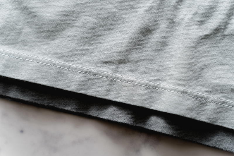 Close up of a light green Mott & Bow t-shirt's bottom stitching