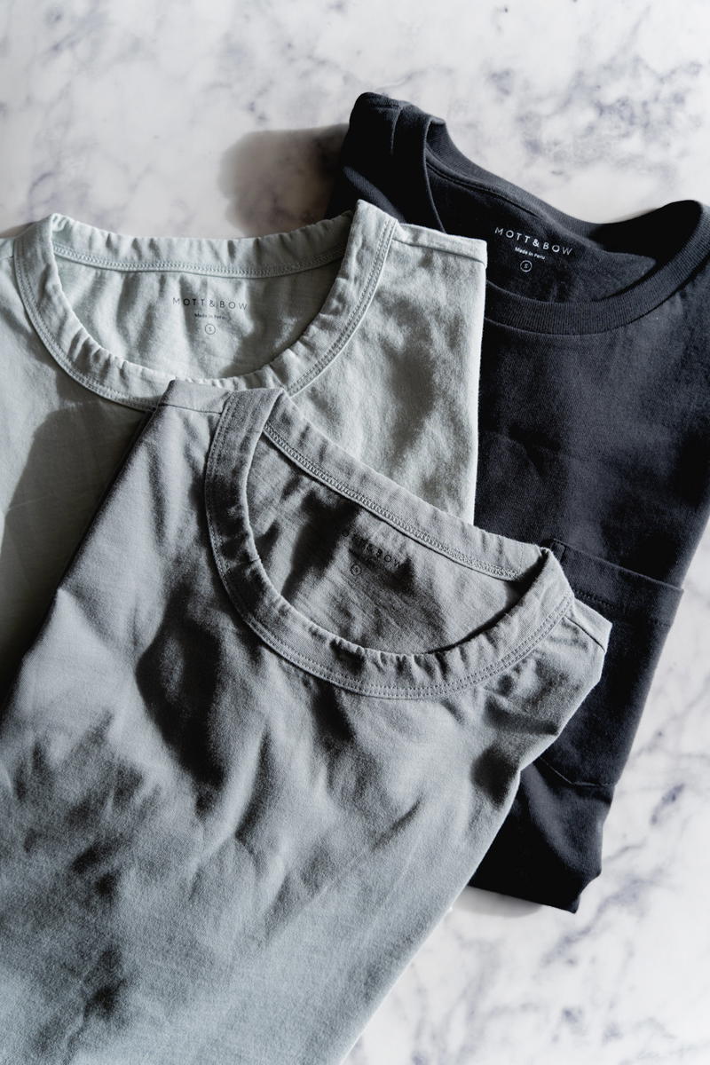 Three Mott & Bow t-shirts on a marble table