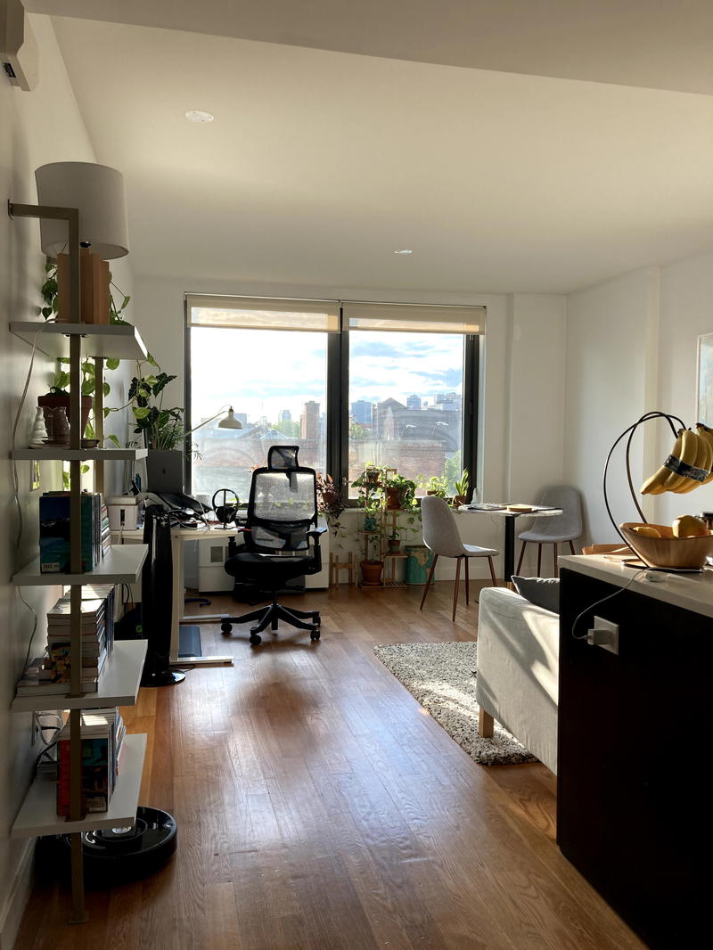 A living room with hardwood floors and a desk.